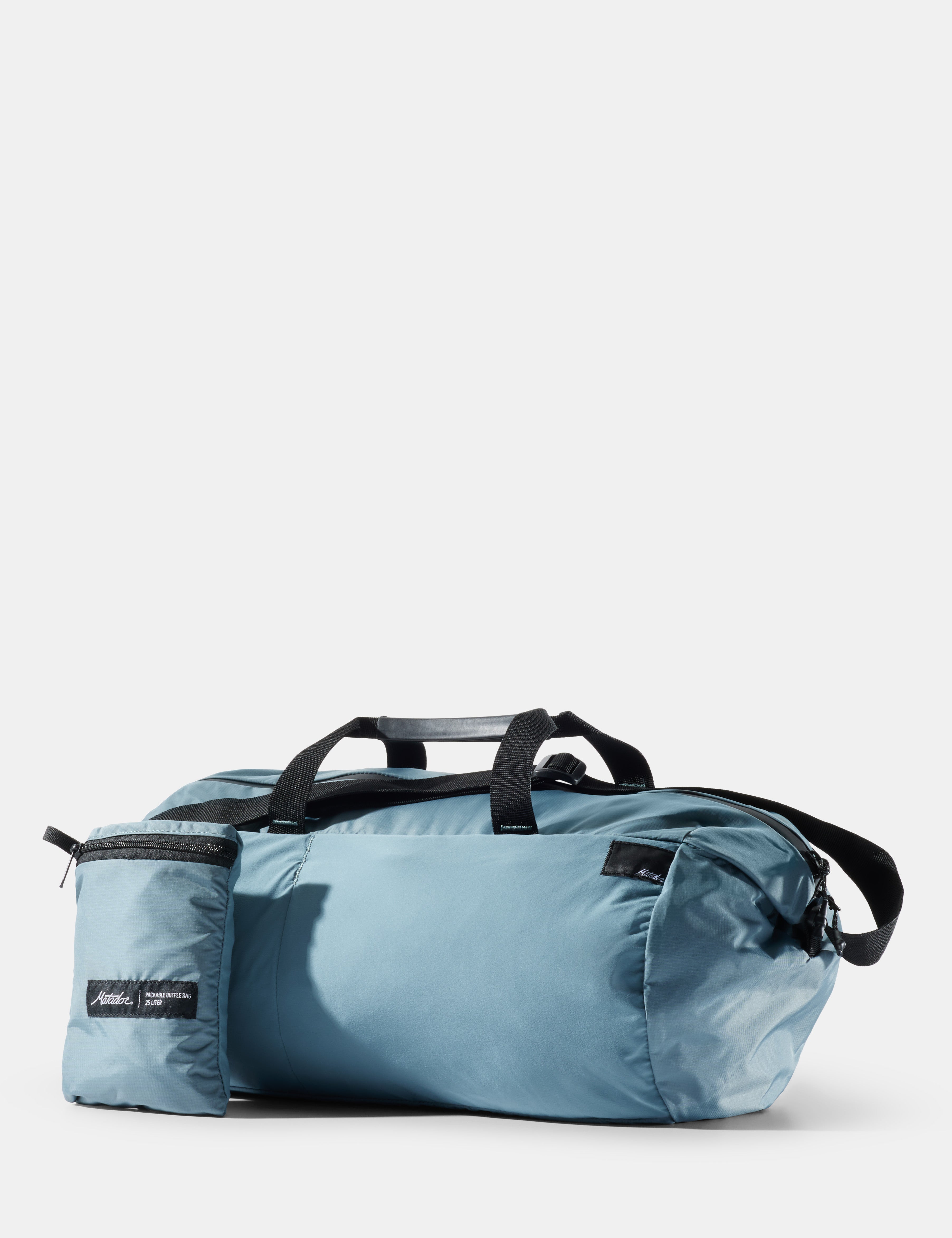 Blue duffel bag with black straps on a light gray background